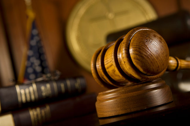 A judge's gavel sits on a wooden table, symbolizing the authority to deliver judgments on charges.