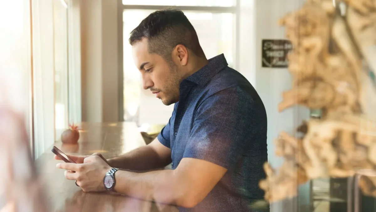 Man sitting at a table focused on his smartphone.