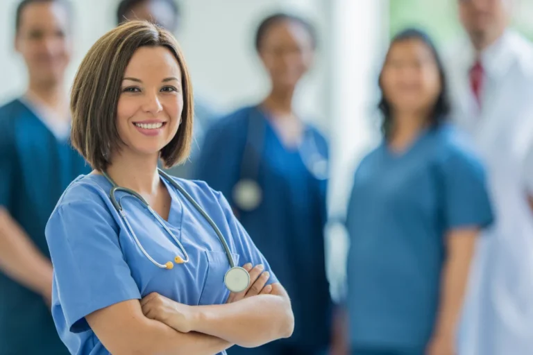 A confident healthcare professional smiling in the foreground with a team of medical staff in the background.