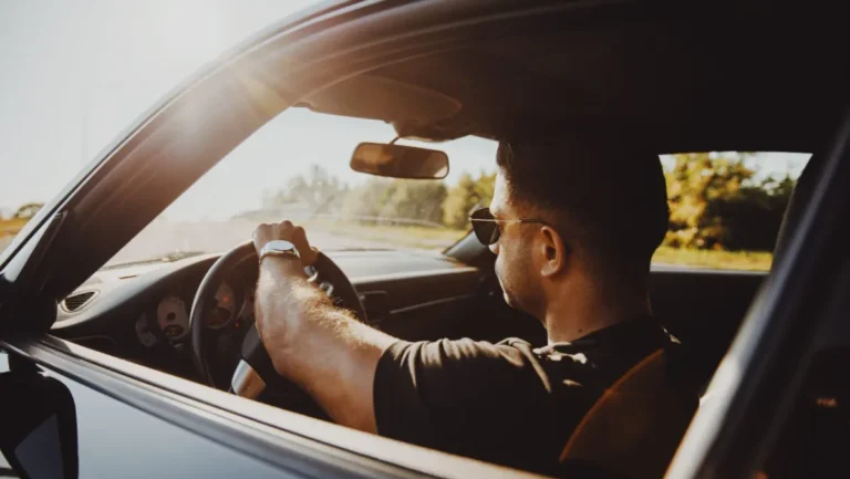 Man driving a car during sunset.