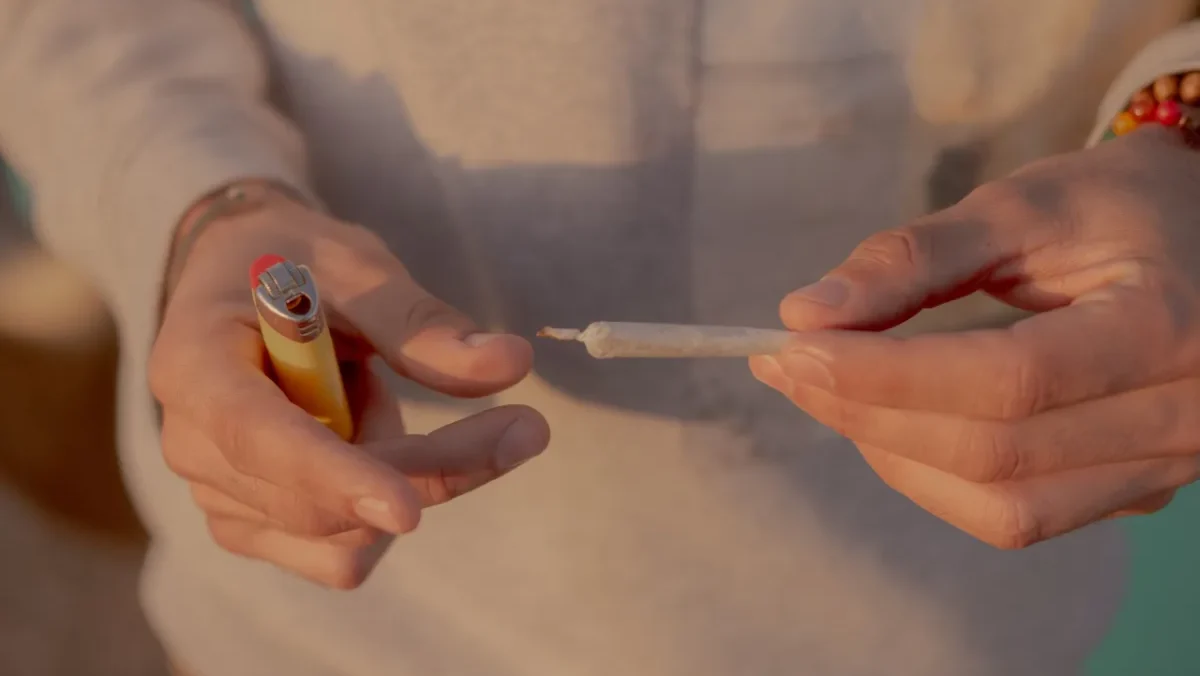 Person holding a rolled cigarette and a lighter.