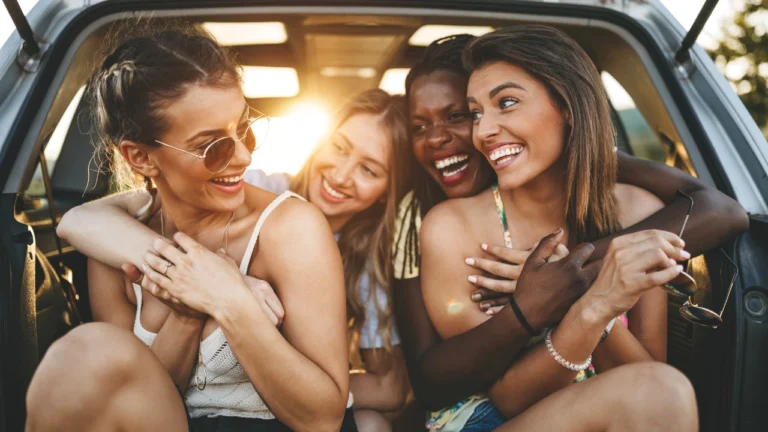 Four friends sharing a joyful moment in the trunk of a car in Texas.