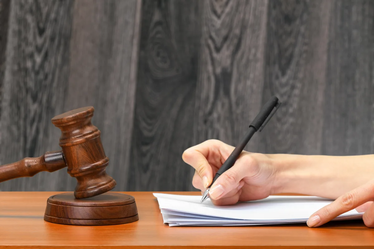 A judge's hand writing on a piece of paper with a gavel, discussing a probation violation case for a driver charged with a misdemeanor.