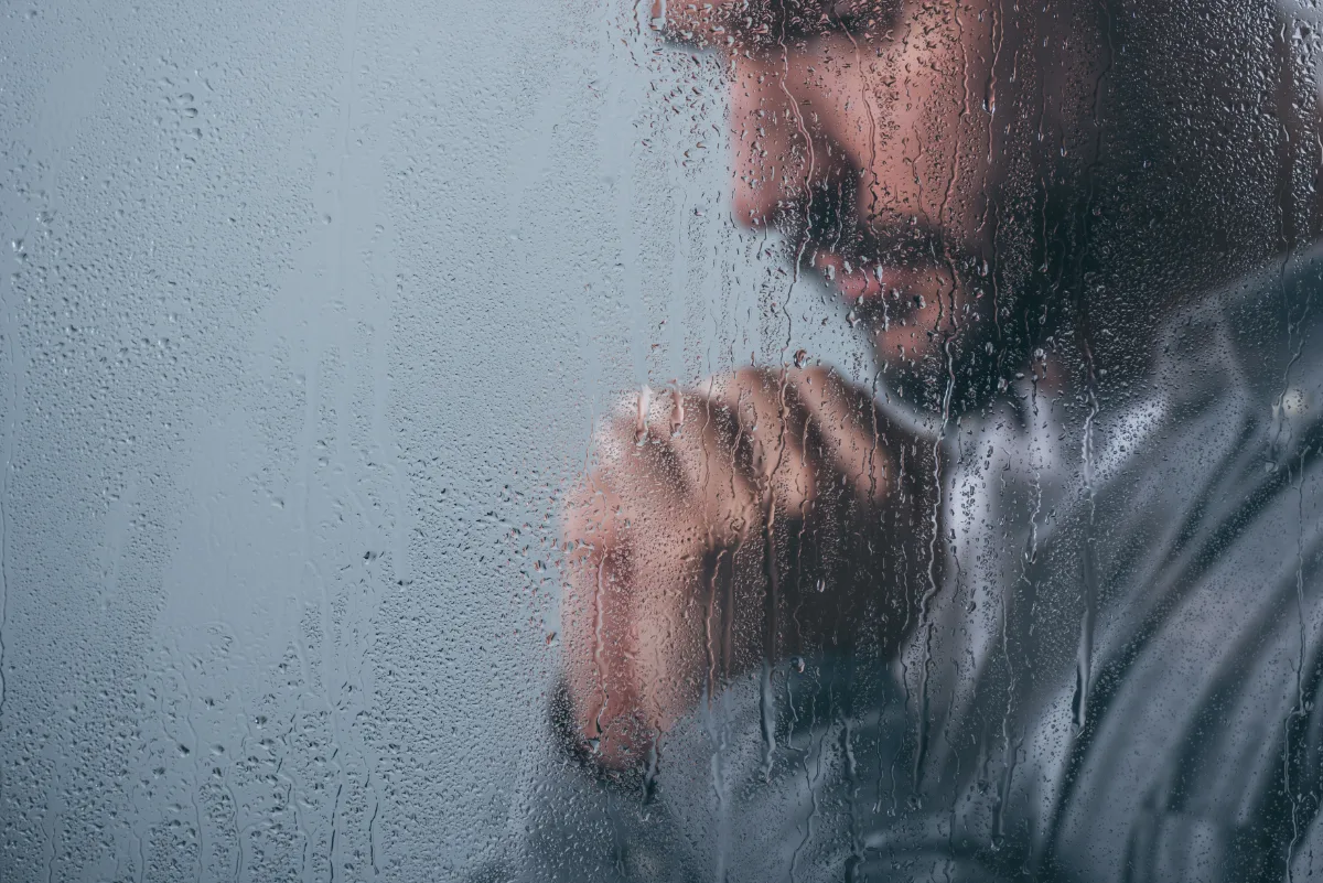 A probationary driver peering through a rainy window, contemplating the charges against him.