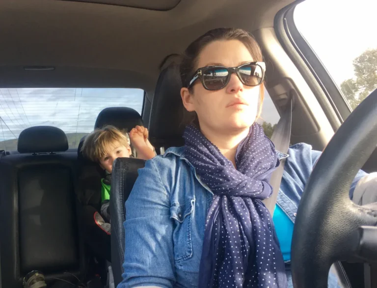 Woman driving a car with a child in the back seat.