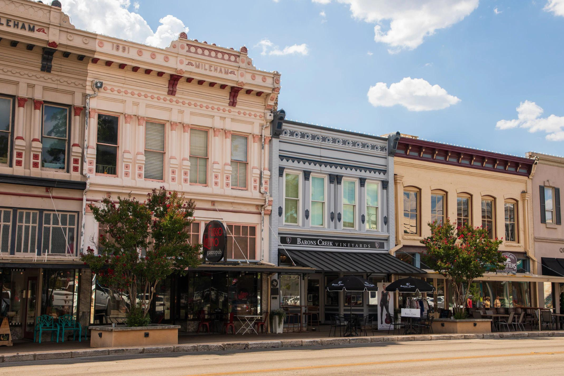 Historic downtown street with three colorful vintage storefronts, featuring intricate architectural details and outdoor seating under the blue sky—a charming contrast to Georgetown's efforts in managing public intoxication.