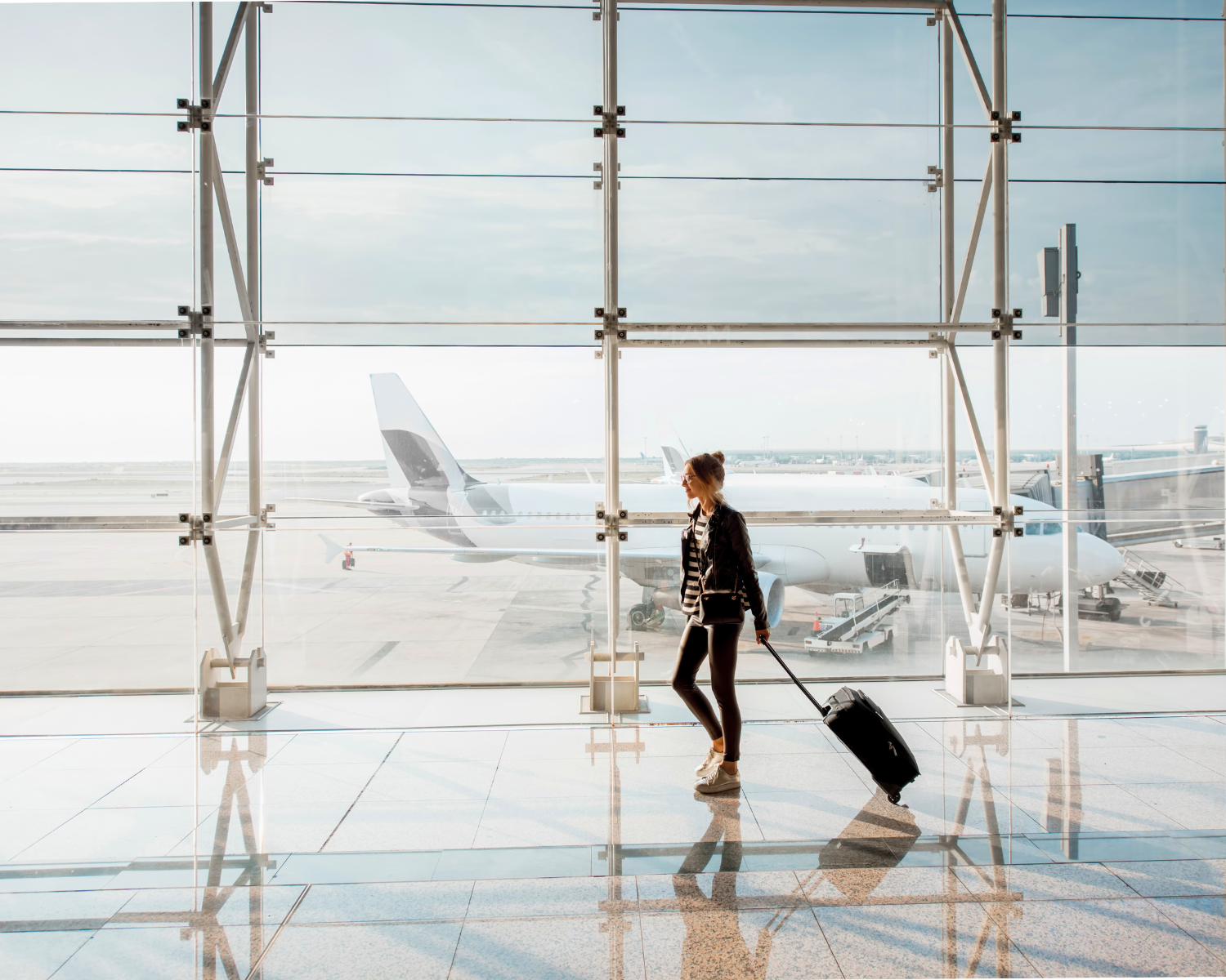 A person, perhaps weary from travel, strolls through Grapevine airport terminal with a suitcase as a plane awaits beyond the expansive windows—hopefully avoiding any incidents of public intoxication along the way.