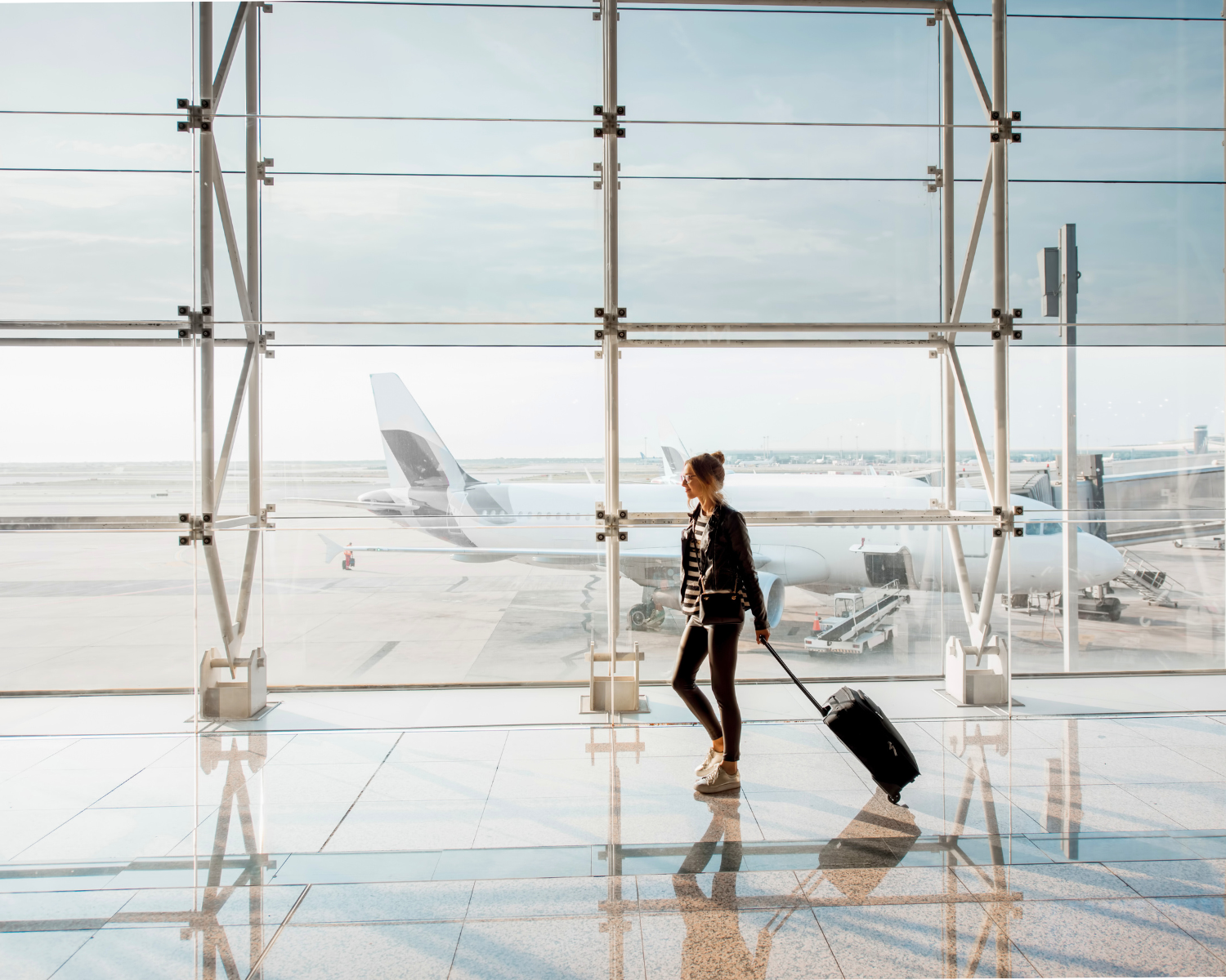 A traveler strides through the bustling airport terminal, their suitcase rolling smoothly behind them. Through the large window, a plane awaits its next journey. Much like a Grapevine expungement lawyer navigating complex legal paths, this traveler is focused on reaching their destination seamlessly.