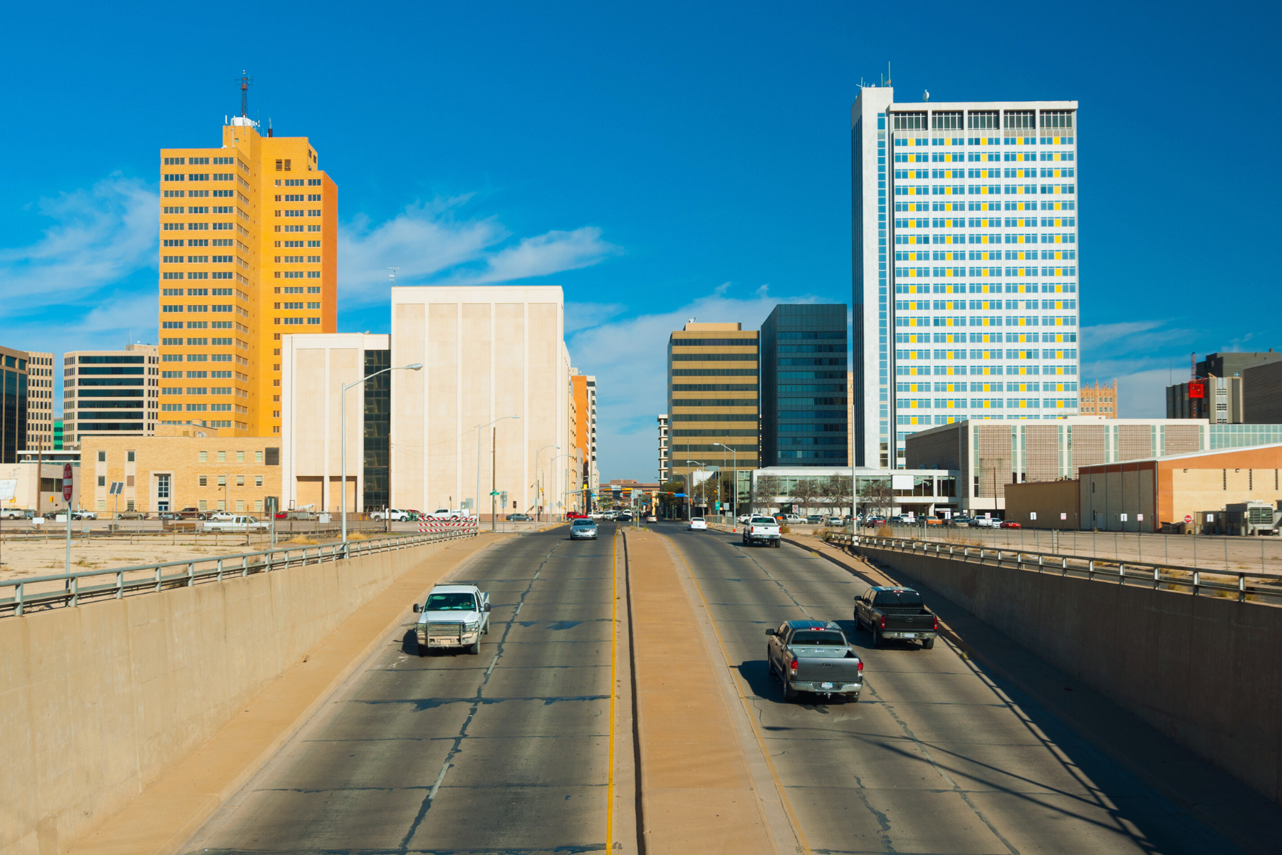 A wide view of a city street in Midland with cars and tall buildings under a clear blue sky, seemingly unaware of the previous night's public intoxication incidents.