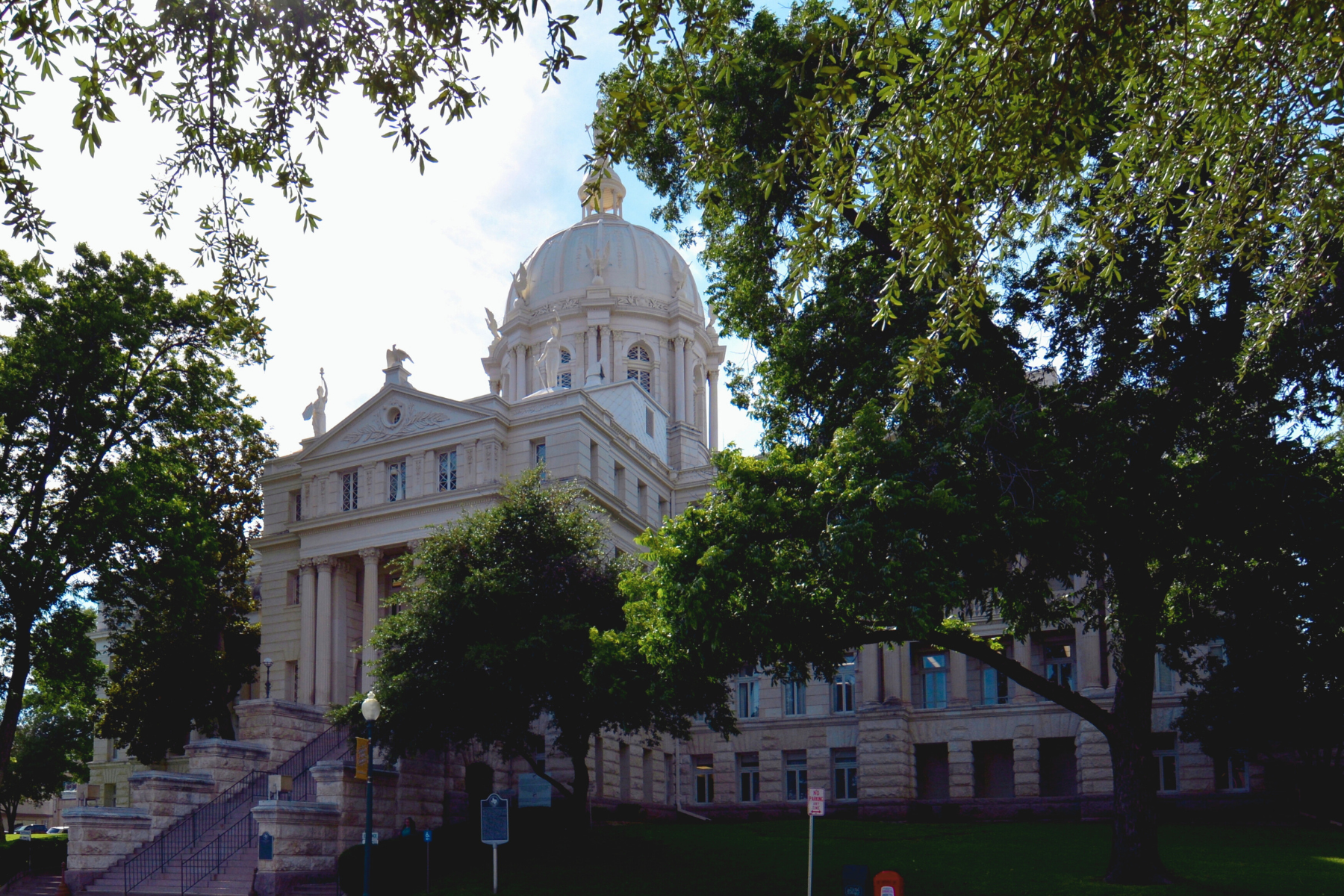 A historic domed building surrounded by trees, known for its classical architecture with columns and statues, is locally famed as a serene escape from the bustle yet often finds itself at the center of tales involving public intoxication in Waco.